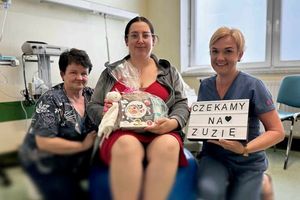 Kobieta w ciąży z osobami towarzyszącymi, tablica z napisem